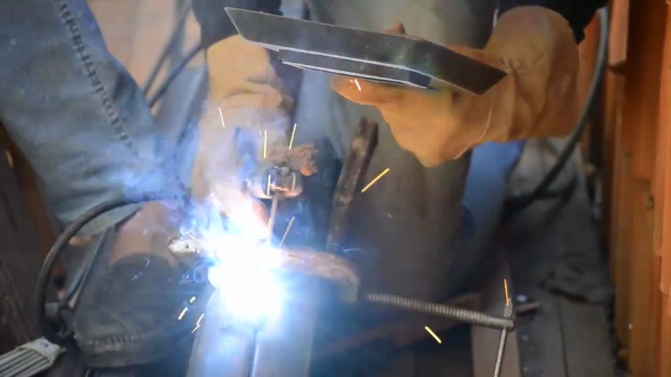 Welder fusing a heavy steel trailer frame joint